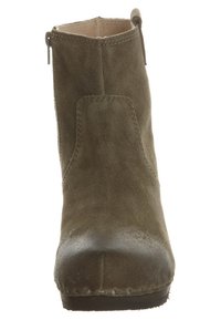 Ruskeat mokkasiiniset nilkkakengät, joissa on sivuvetoketju, pyöreä etuosa, tikattu yksityiskohtia ja vetokahva takana.