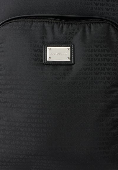 Sac à dos noir avec motif logo Emporio Armani répété, poche avant zippée et plaque en métal argentée Emporio Armani sur la poche.