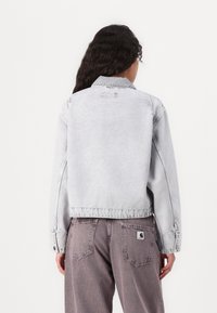 Grå denimjakke med en kortet design, med klassisk krage, lange ermer og knaplukking i ermene. Merkeverdige sømdetaljer og subtil merkevare.