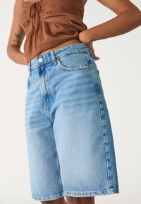 Ljusblå denimshorts med en lös passform och ingen synlig slitage. Har hög midja och klassisk fem-fickorsdesign.