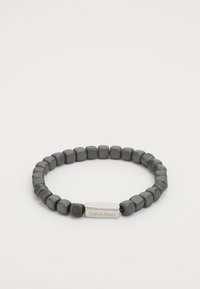 Grau perlenarmband mit quadratischen steinen in glatter textur, akzentuiert durch eine rechteckige silberfarbene logo-platte von calvin klein.
