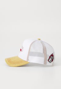 White cap with mesh back, yellow corduroy bill, red stitching, and embroidered flame design with a skull detail on the side.