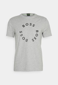 Světlé šedé tričko s krátkým rukávem a černým kruhovým potiskem textu "BOSS" na přední straně a kulatým výstřihem.