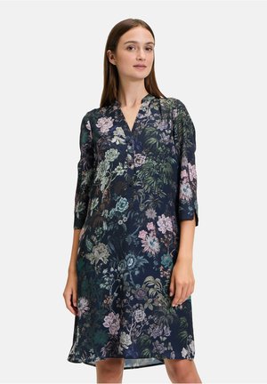 Blumendruckkleid mit navy-blauem Grundton, Dreiviertelärmeln, V-Ausschnitt und Knopfdetails. Besitzt eine fließende, leichte Stofftextur.