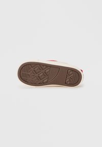 Semelle en caoutchouc marron avec un motif de semelle triangulaire, base beige ; design minimaliste avec des accents rouges sur le côté.