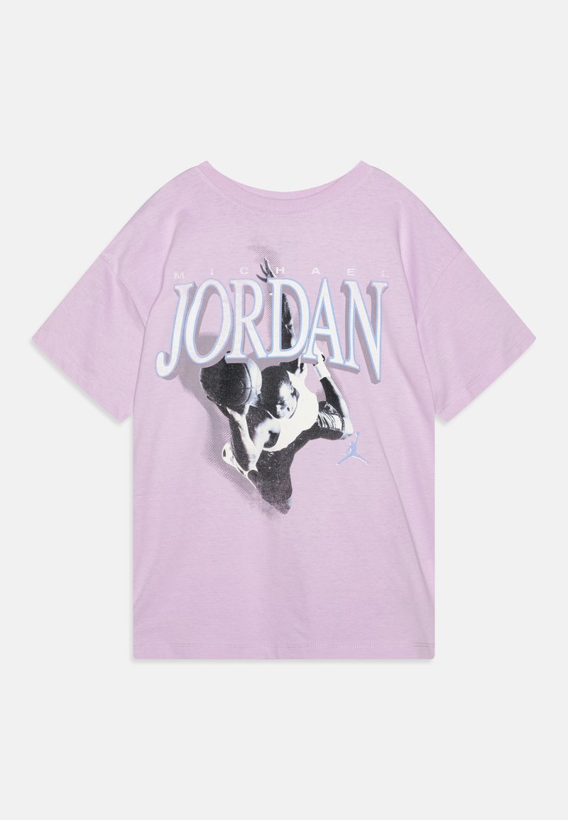 Lila pamut póló, amelyen egy kosárlabdázó grafikus nyomata található, felette pedig vastag betűkkel a "MICHAEL JORDAN" felirat olvasható.