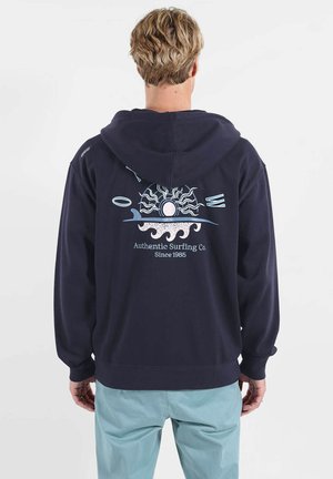 Sweat à capuche bleu marine avec un imprimé graphique de rayons de soleil et de vagues dans le dos, fabriqué en mélange de coton doux.