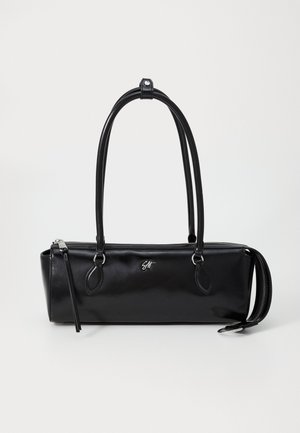 Sac à main rectangulaire noir avec double poignée, fermeture éclair argentée et petit logo argenté sur une surface en cuir lisse sur fond uni.
