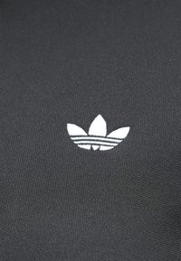 Μαύρο ύφασμα με λευκό, τριφύλλι με τρία φύλλα λογότυπο με τρεις οριζόντιες ρίγες, υφή επιφάνειας και κομψό, μινιμαλιστικό σχέδιο.