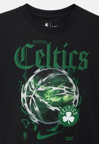 Camiseta negra con texto verde "Boston Celtics", gráfico abstracto de baloncesto plateado, logo de trébol verde y logotipos de la NBA y Nike.