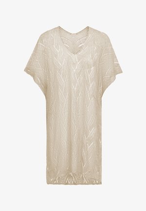 Beige kötött felső, V-nyakkivágással, széles ujjal, csipkés mintával, amely cikk-cakk mintákat és nyitott szemeket tartalmaz, így lélegző textúrát biztosít.