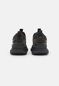 Chaussures de sport noires présentant un dessus texturé avec des accents décoratifs, des languettes de tirage et des semelles rembourrées pour un confort supplémentaire.