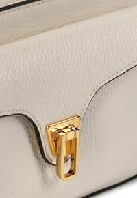 Handtas van crèmegekleurd leer met een gestructureerde afwerking, voorzien van een goudkleurige sluiting en zwarte stiksels langs de randen.