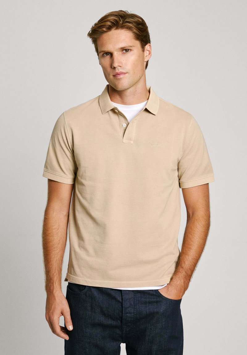 Bežna polo majica izrađena od pamuka, kratkih rukava, s dvobotonim kopčanjem i suptilnim logotipom na prsima. Nosena je s tamnim trapericama.