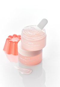 Maschera notturna Abib PDRN collagen in un barattolo trasparente con coperchio bianco, con una consistenza gelatinosa rosa chiaro. Accompagnata da una spatola in silicone rosa e una goccia di gel.