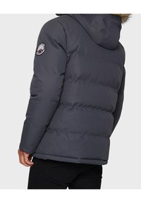 Mørkegrå dunjakke med hætte, der har vandret syninger, en rund logo-patch på venstre ærme og en glat stofstruktur.