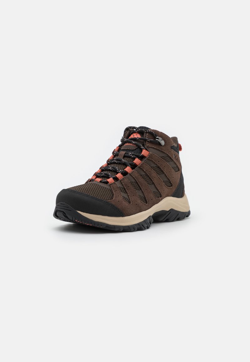Scarpa da trekking marrone con una combinazione di materiali in suede e mesh. Suola in gomma nera con lacci e dettagli rossi. Design mid-top.