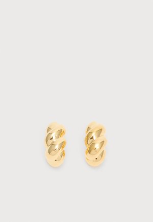 Pár lesklých zlatých skrútených kruhových náušníc na jednoduchom svetlom pozadí, zobrazujúce odrazivý leštený kovový povrch.