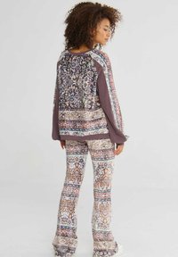 Uitlopende broek en een lange mouwtop met een patchworkontwerp in aardetinten, met intrigerende bloemenpatronen en een relaxte pasvorm.