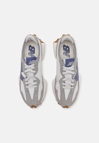 Atletické boty vyrobené z kombinace šedých a bílých textilních materiálů, s tmavě modrým akcentem, gumovou podrážkou a standardním šněrováním.