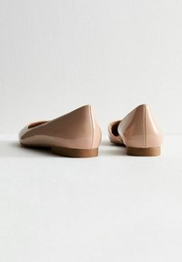 Glansiga nakna ballerinaskor med rund tå och låg klack. Texturerat syntetmaterial med en slät yta, som har en minimalistisk design.