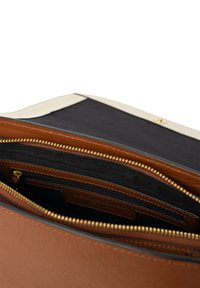 Braune Lederhandtasche mit goldenem Reißverschluss, ausgestattet mit einem Innenraum, der mit schwarzem Stoff ausgekleidet ist und einem kontrastierenden cremefarbenen oberen Rand.