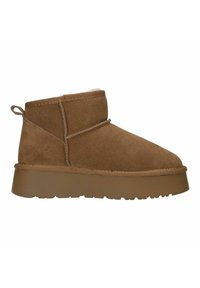Bruine suede enkellaars met een ronde neus, textuur aan de buitenkant en een dikke, stevige bruine zool. Heeft stiksels en een trekband op de hiel.