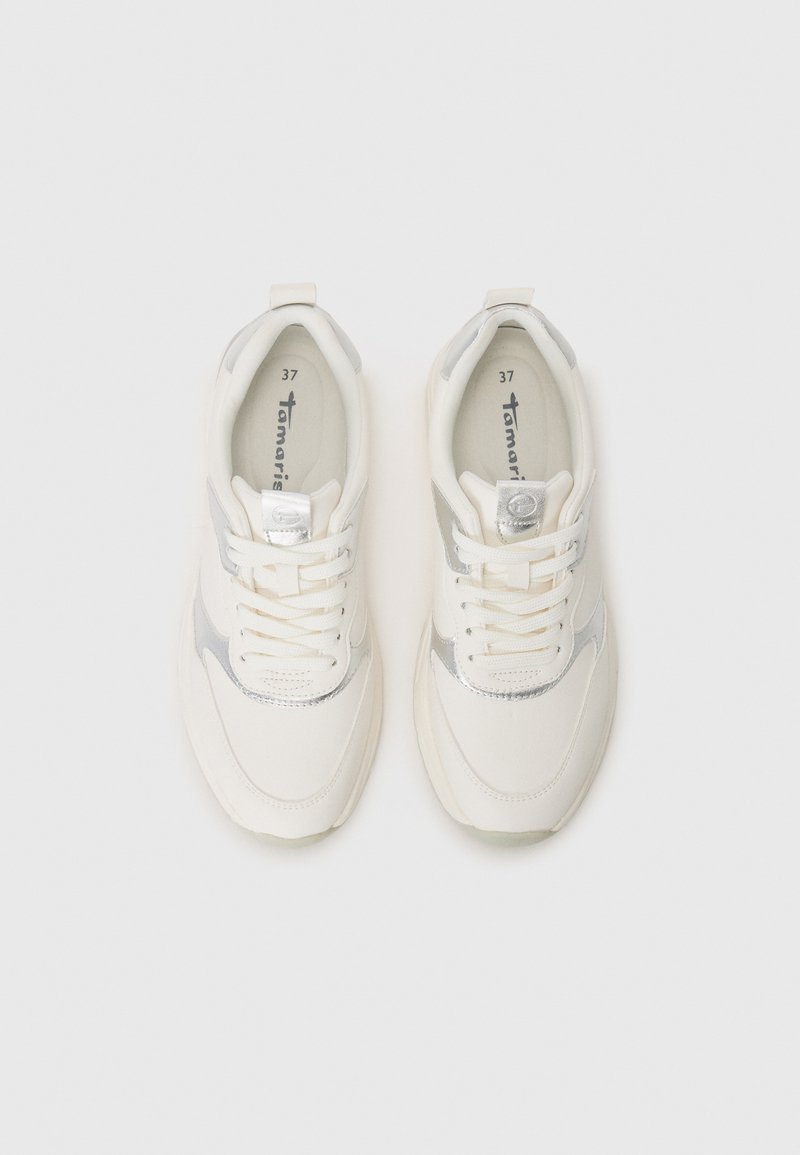 Baskets blanches avec accent argenté, en tissu et matériaux synthétiques, bout arrondi, design à lacets, et logo sur la semelle intérieure. Taille 37.
