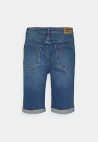 Tumši zils džinsi šorti ar neapstrādātu apakšmalu un sarullētām piedurknēm. Iekļauj aizmugures kabatas un ādas logo uz jostas.