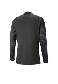 Chemise à manches longues noire, présentant un corps texturé et des manches à motifs avec de petites formes géométriques. Col classique, ourlet droit.