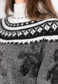 Gray knit sweater with a high collar. Features black and white geometric patterns across the yoke. Soft, textured wool material.