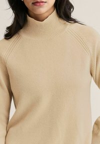 Beige ribbattu pepitoni nälkäpaita, jossa on tiukka malli, raglan-hihat ja pehmeä rakenne. Liukas pinta, jossa on hienovaraisia ompelutietoja.