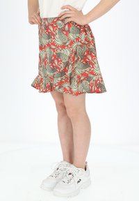 Rød nederdel med et paisley mønster i creme og blå, flared kant, lavet af letvægtsstof. Bærer den med hvide sneakers.