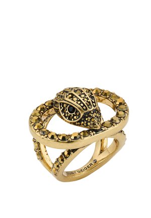Bague en ton or ornée d'une tête de serpent avec des strass noirs et dorés entourant l'anneau, signée Kurt Geiger à l'intérieur.