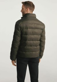 Zielono-oliwkowa pikowana kurtka z wysokim kołnierzem, poziomym przeszyciem i dopasowanym krojem. Posiada naszywkę z logo na lewym rękawie.