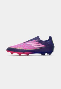 Botas de fútbol con un diseño en degradado, que va de morado a rosa, parte superior texturizada y múltiples tacos en colores contrastantes.