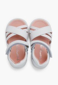 Sandalias de cuero blanco con tiras entrelazadas, correa gris en el tobillo, forro interior rosa y suela blanca. Presenta una marca plateada en el interior.