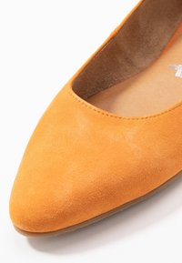Scarpa piatta in suede arancione con punta affusolata e scollatura bassa. Texture liscia con un interno leggermente imbottito. Suola di tonalità chiara.