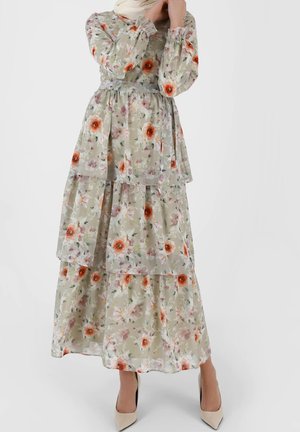 Robe maxi florale en vert clair avec un design superposé, ornée de fleurs orange et violettes, à manches longues et à taille nouée.