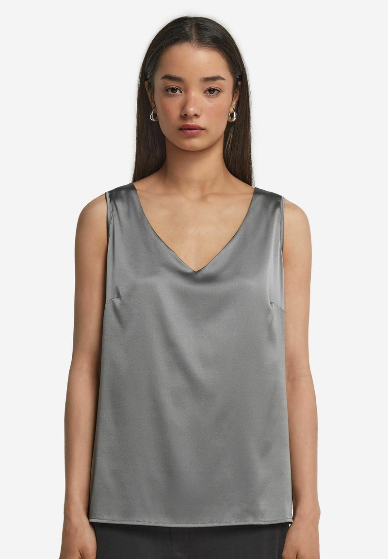 Grå satin sleeveless topp med V-ringning, slät textur och enkel design med minimal sömnadsdetalj längs fållen.