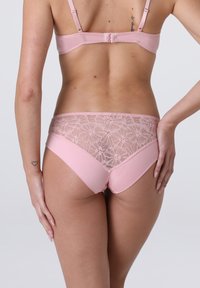 Completo di lingerie rosa chiaro caratterizzato da un davanti in satin liscio e un retro in pizzo floreale, con spalline regolabili e dettagli di orlo delicati.
