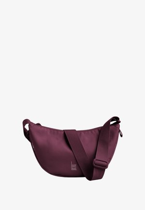 Sac à épaule bordeaux en tissu doux avec une bandoulière réglable, fermeture éclair et un logo discret imprimé sur le côté.