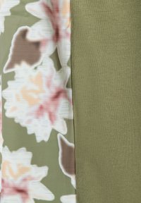 Floral patterned fabric in shades of green, pink, and beige on one side; solid olive green textured fabric on the other.