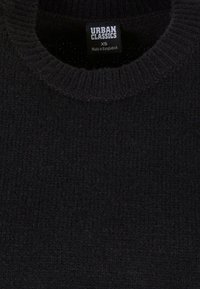 Zwarte gebreide trui met een ronde hals, gemaakt van zacht materiaal. Label toont "Urban Classics XS." Textuur lijkt dik en gezellig.