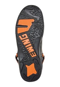 Černá lezecká bota má podrážku z texturované gumy s oranžovými akcenty a vzory. Výrazné značení "EWING" tučným písmem.