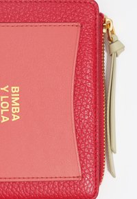Cartera texturizada roja con un panel liso rosa. Presenta herrajes en dorado, cierre de cremallera y el nombre de la marca embellecido "BIMBA Y LOLA."