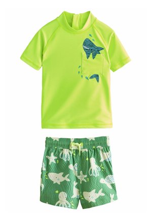 Neon grøn kortærmet rash guard med en fiskelomme, parret med grønne badeshorts med et mønster af havdyr i hvidt og blåt.