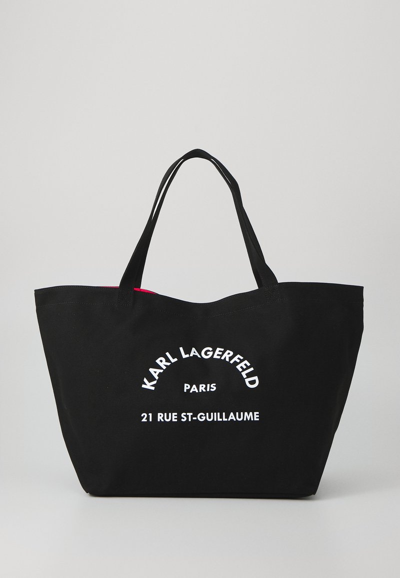 Sac fourre-tout en coton noir avec de doubles poignées, présentant un logo en texte blanc "KARL LAGERFELD PARIS" et "21 RUE ST-GUILLAUME" sur le devant.