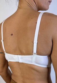 Sujetador blanco con tirantes ajustables, cierre trasero elegante y encaje en el borde superior, mostrado desde la perspectiva trasera.