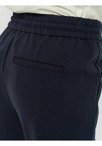 Mörkblå polyesterblandning träningbyxor med resårmidja, utrustade med en liten, slimmad bakficka. Mjuk textur och avslappnad stil.